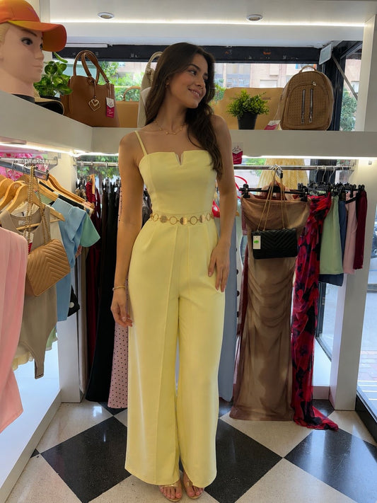 Woman in a yellow dress standing in a clothing store with racks and bags in the background.